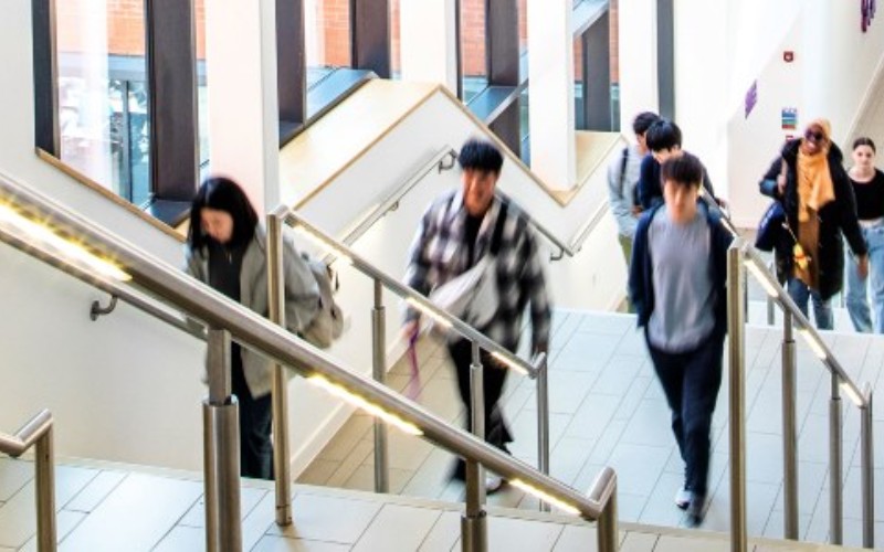 Students walking up a staircase with metal handrails