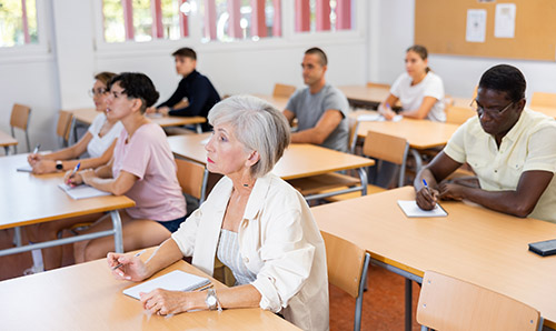 Adult learners attending a classroom lesson and taking notes.