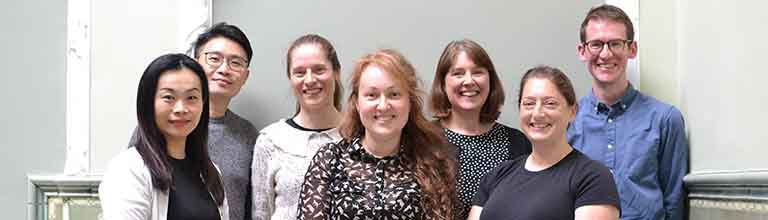 A group of staff members standing closely together and smiling at the camera